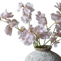 Pink artificial orchids in a textured vase on a white background