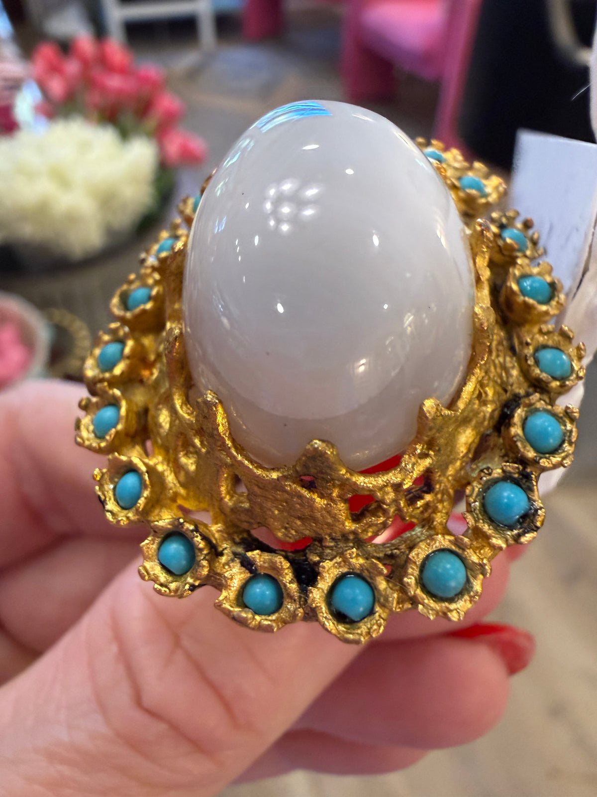 	Close-up of milky-white cabochon surrounded by turquoise-blue accents in a gold-tone vintage ring