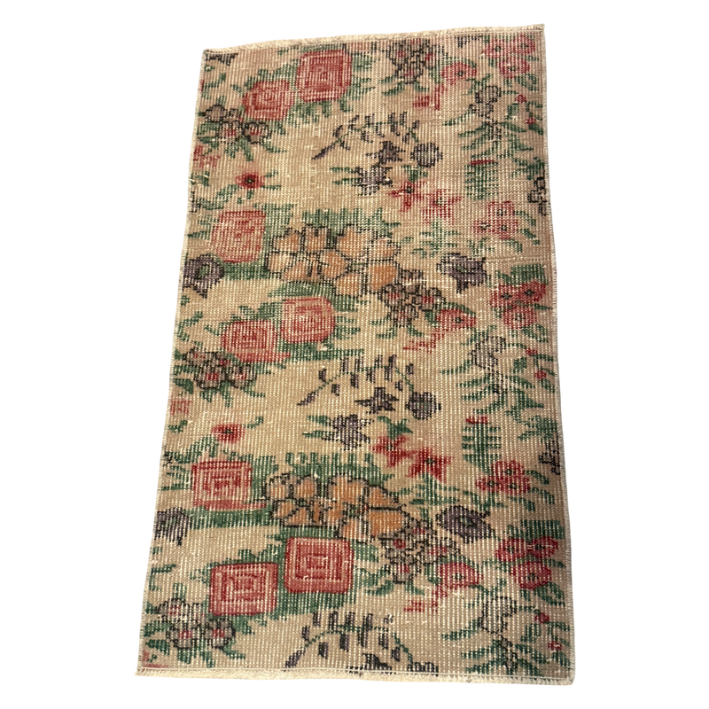 Cream mini rug with an allover pattern of rose-red and apricot flowers, green leaves, charcoal details, and short cream fringe.