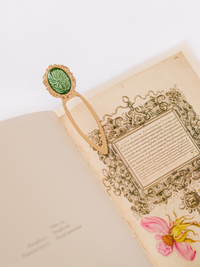 Decorative bookmark with green emblem on an open book with floral design