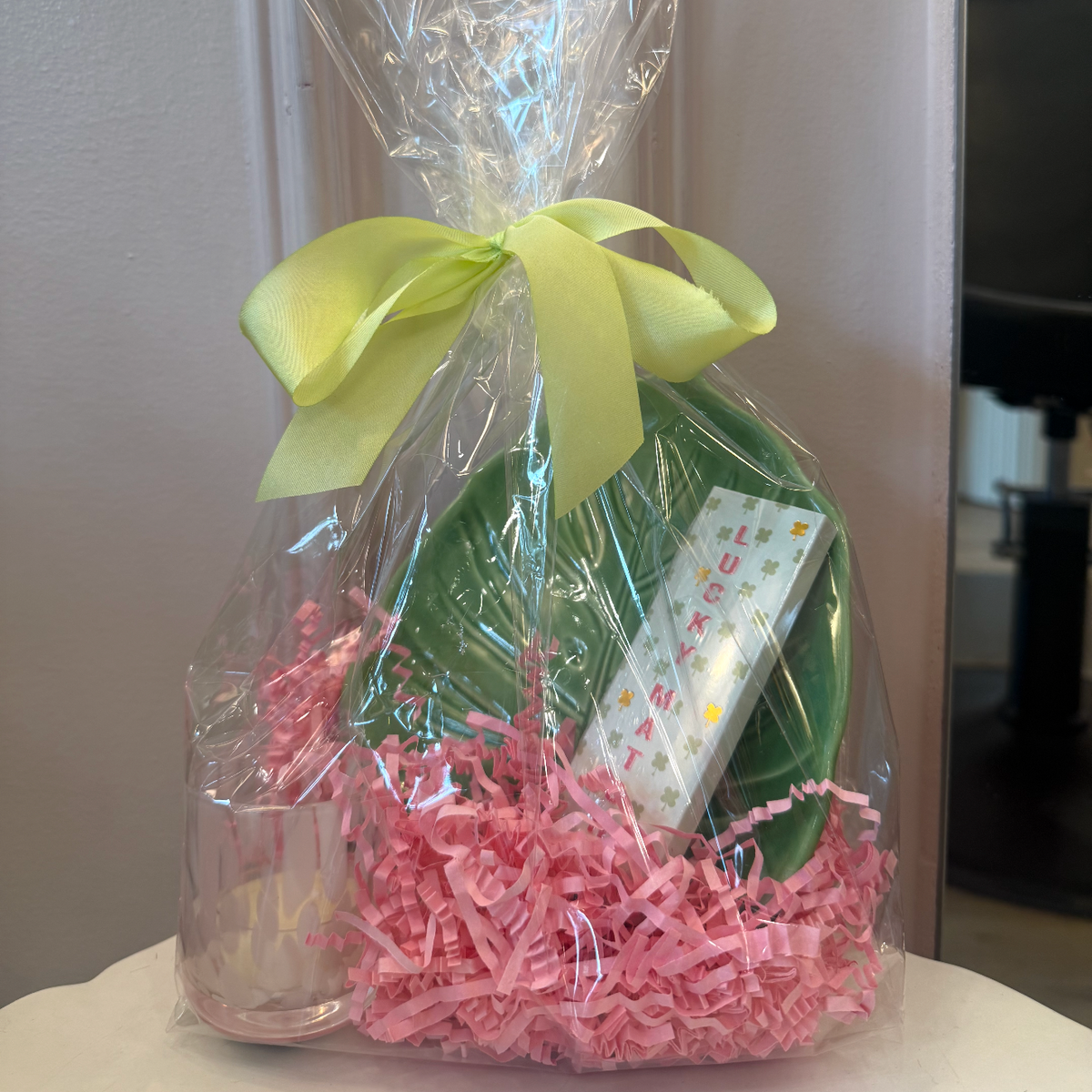 Gift wrapped in clear cellophane with pink tissue paper and a green bow.