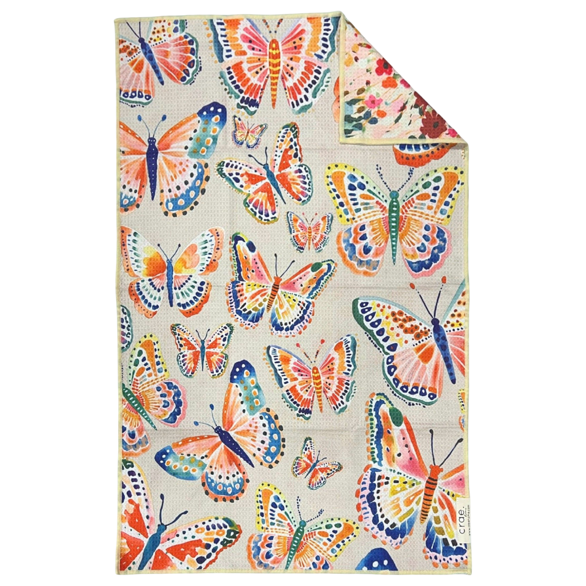 Crae.Home Floatie reversible hand towel hanging with colorful whimsical fish print on a cream background and pink floral reverse