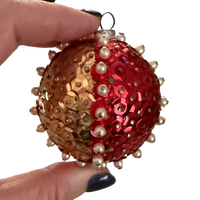 Vintage ball ornament with alternating red and gold-tone sequin panels, raised pearl-look bead borders, and a metal hanging loop.