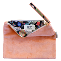 Pink velvet clutch with floral lining and 'Betsy Olmsted' label on a white background