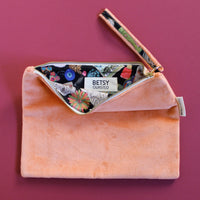 Pink clutch bag with floral patterned interior on a pink background