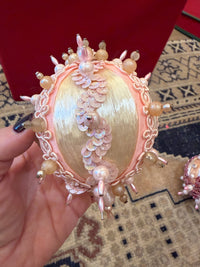 handmade vintage Christmas ornament featuring ivory satin, blush pink pearl embellishments, delicate gold trim, and dangling pink beads.