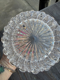 Clear glass dish with intricate patterns held by a person on a dark surface