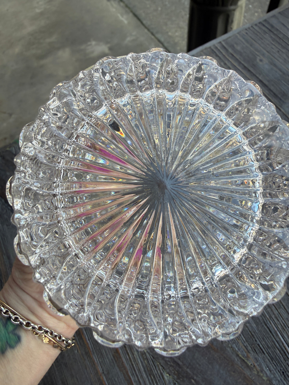 Clear glass dish with intricate patterns held by a person on a dark surface