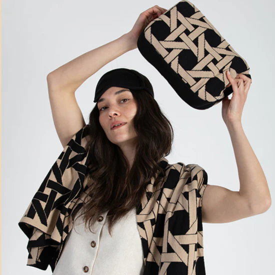 Woman holding a geometric-patterned bag and scarf against a white background