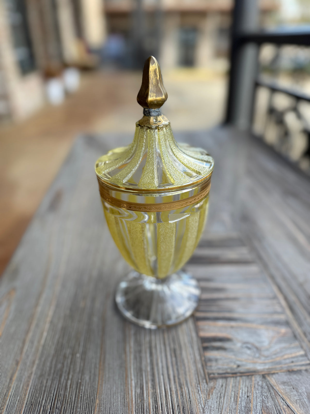 Decorative glass container with a gold lid on a wooden surface