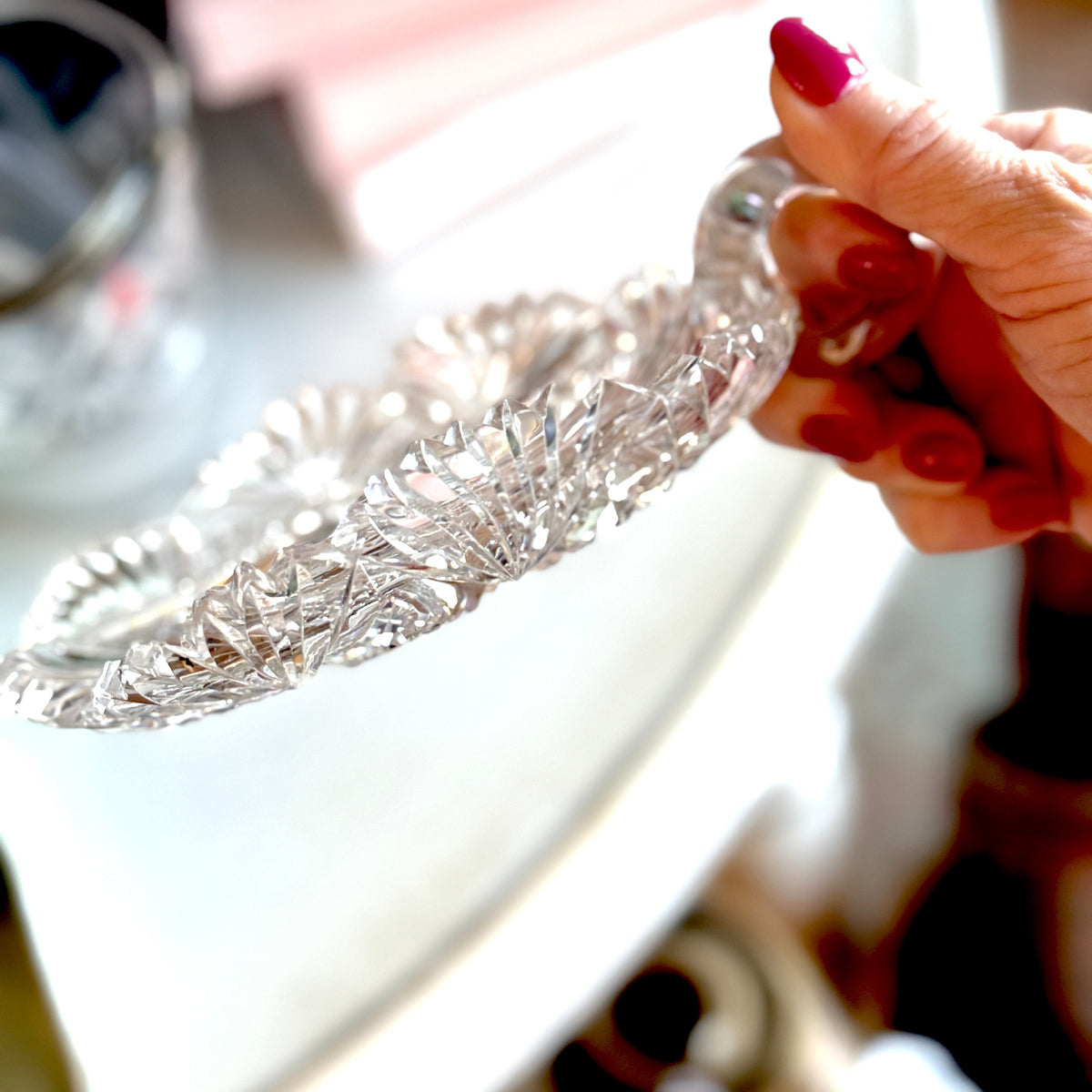Silver bracelet held by a hand with red nail polish on a blurred background