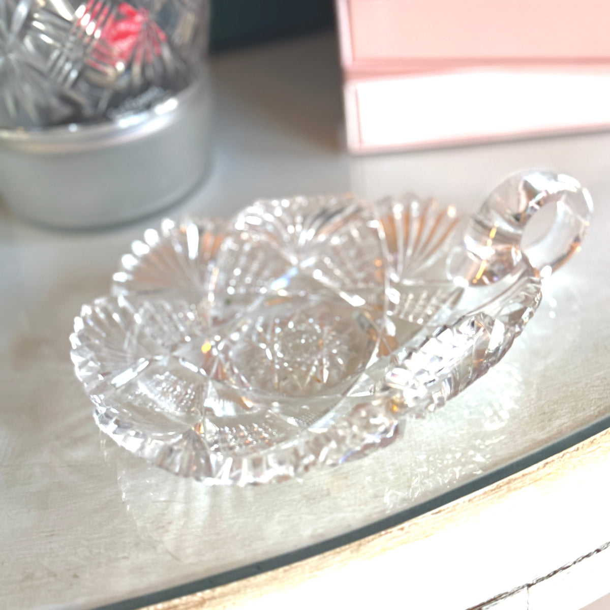 Clear glass candy dish on a reflective surface with a blurred background