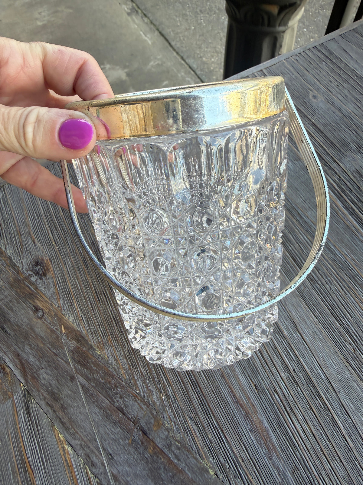 Hand holding a decorative glass item with a metallic rim on a wooden surface